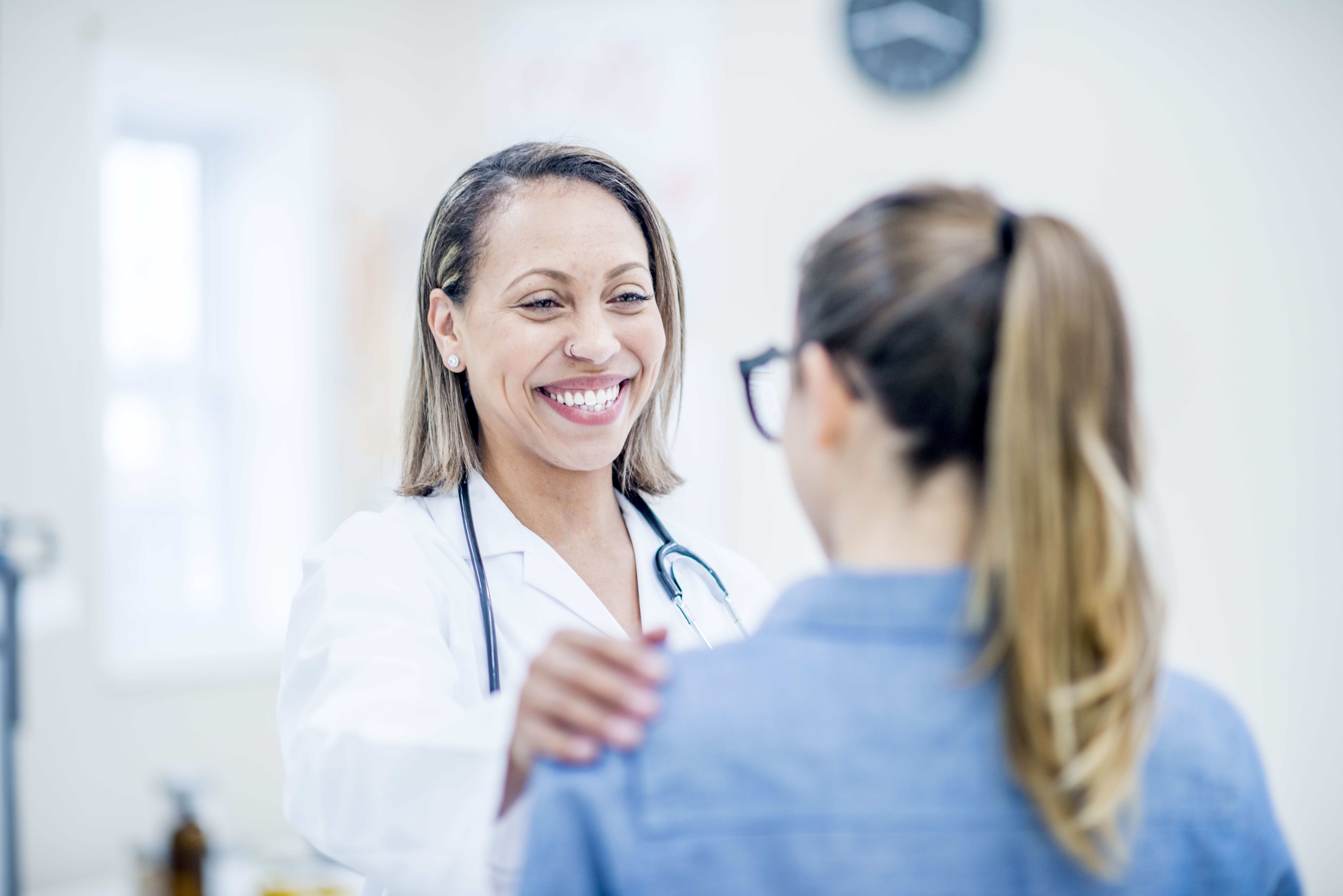 female medical provider smiling with her hand on a patient's shoulder