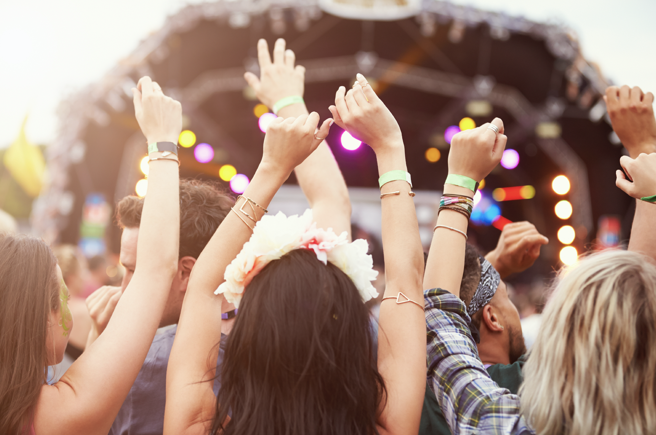 group of people with their arms raised at an outdoor concert