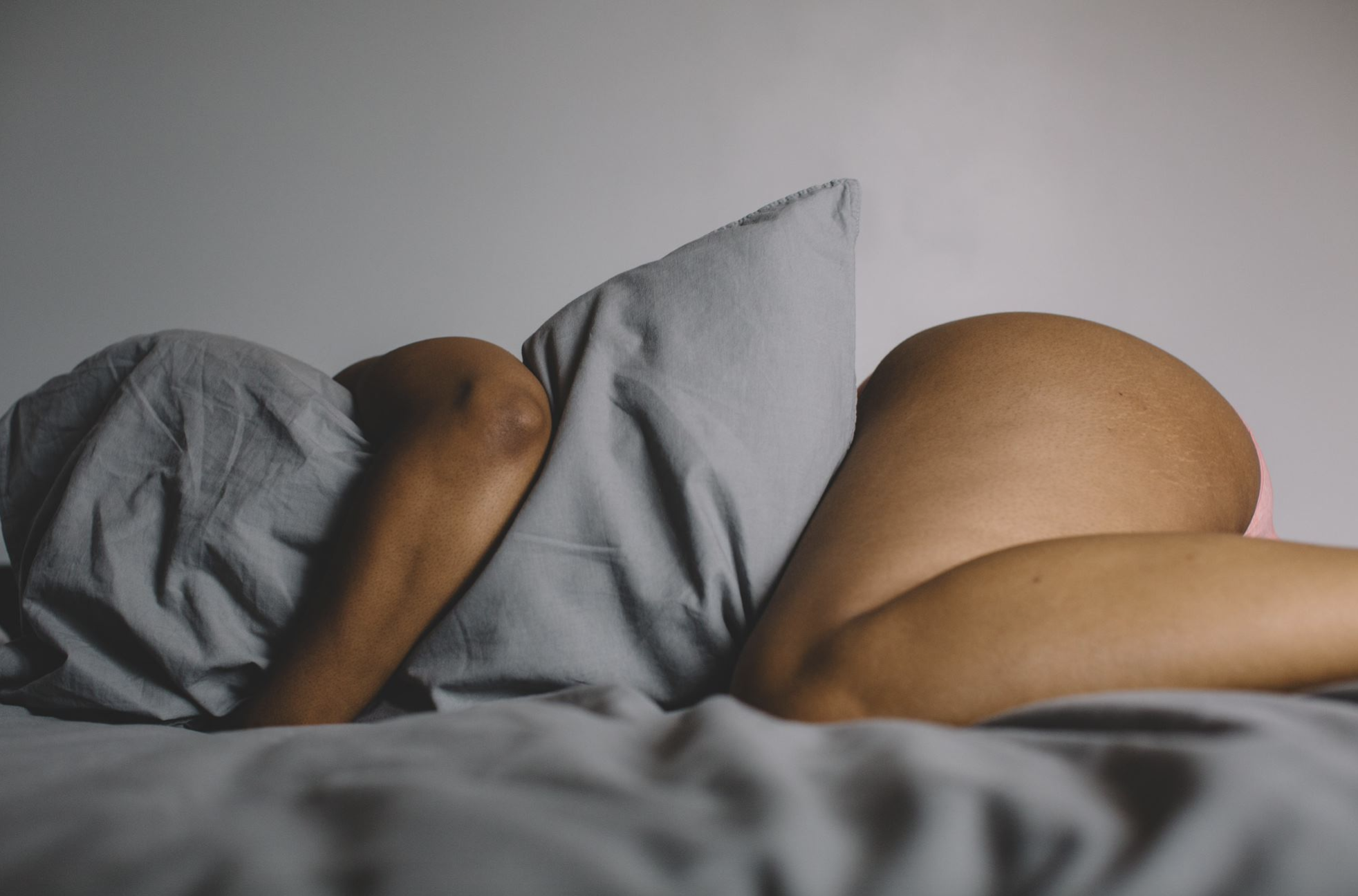 black woman lying in bed and hugging a pillow