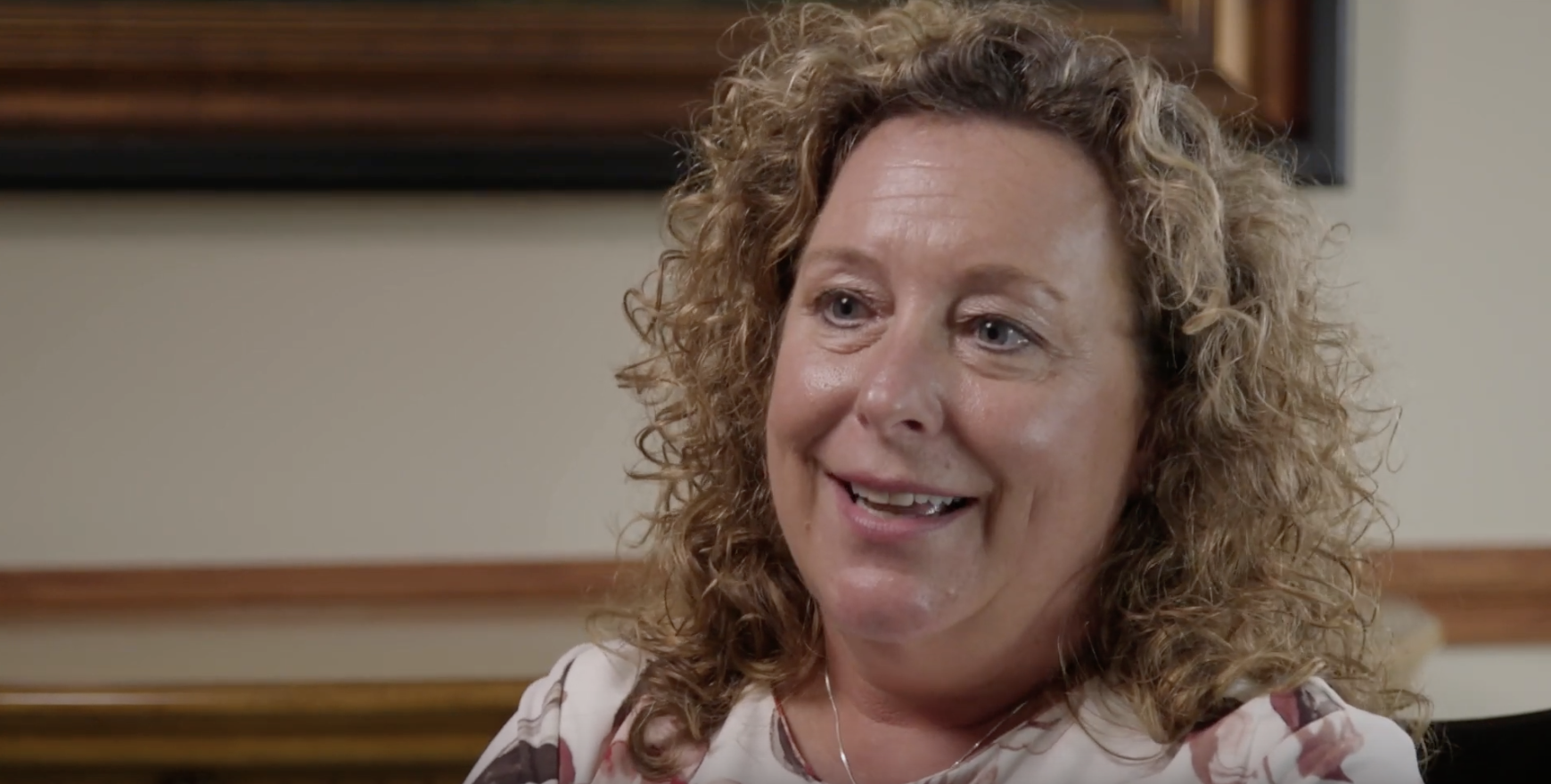 white woman with blonde curly hair being interviewed