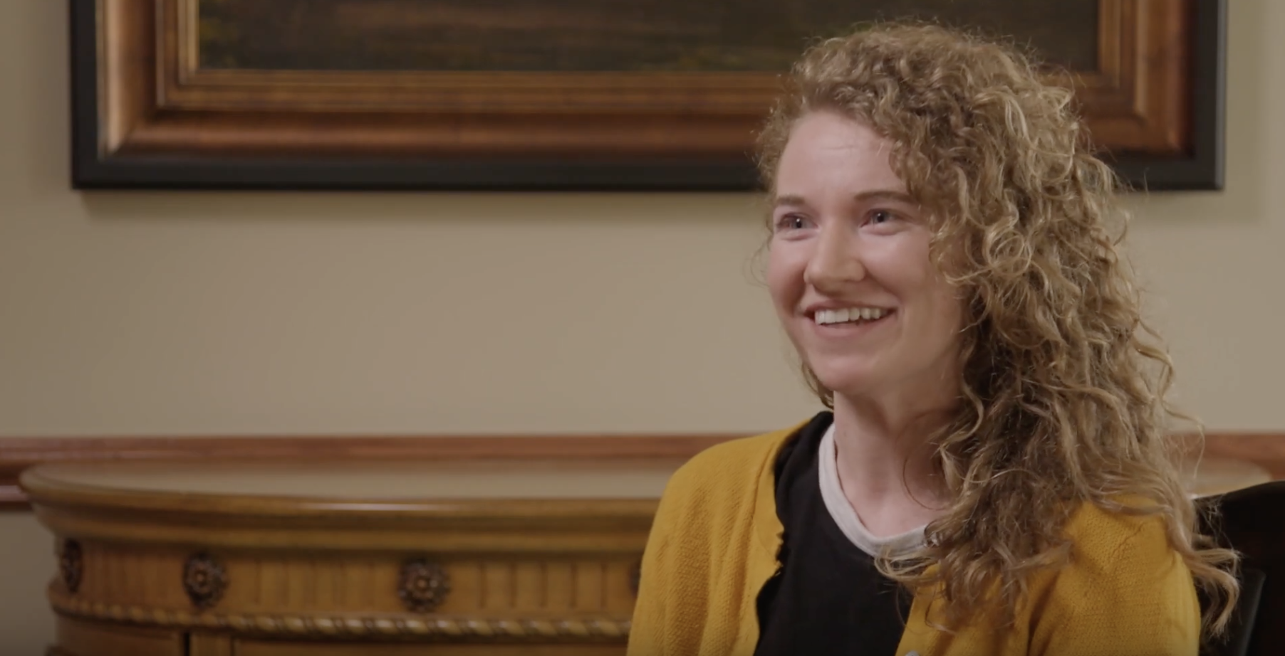 white woman with blonde curly hair being interviewed