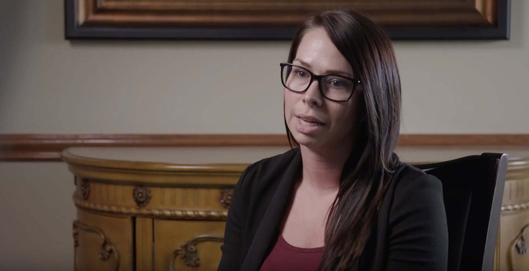 white woman with dark hair and glasses being interviewed