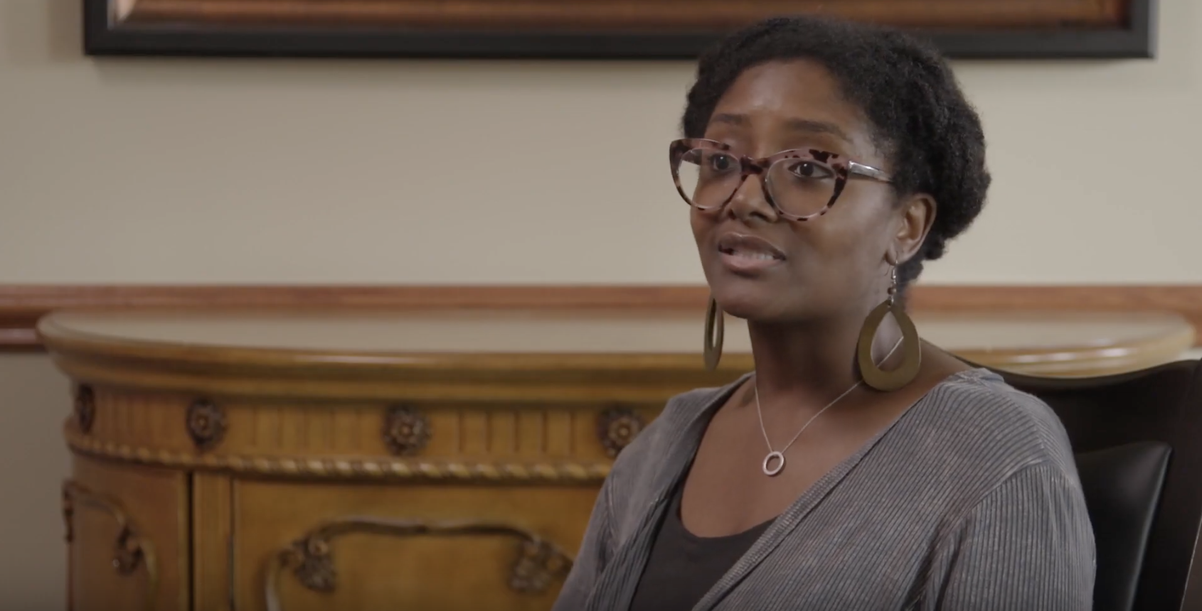 BIPOC woman in glasses being interviewed