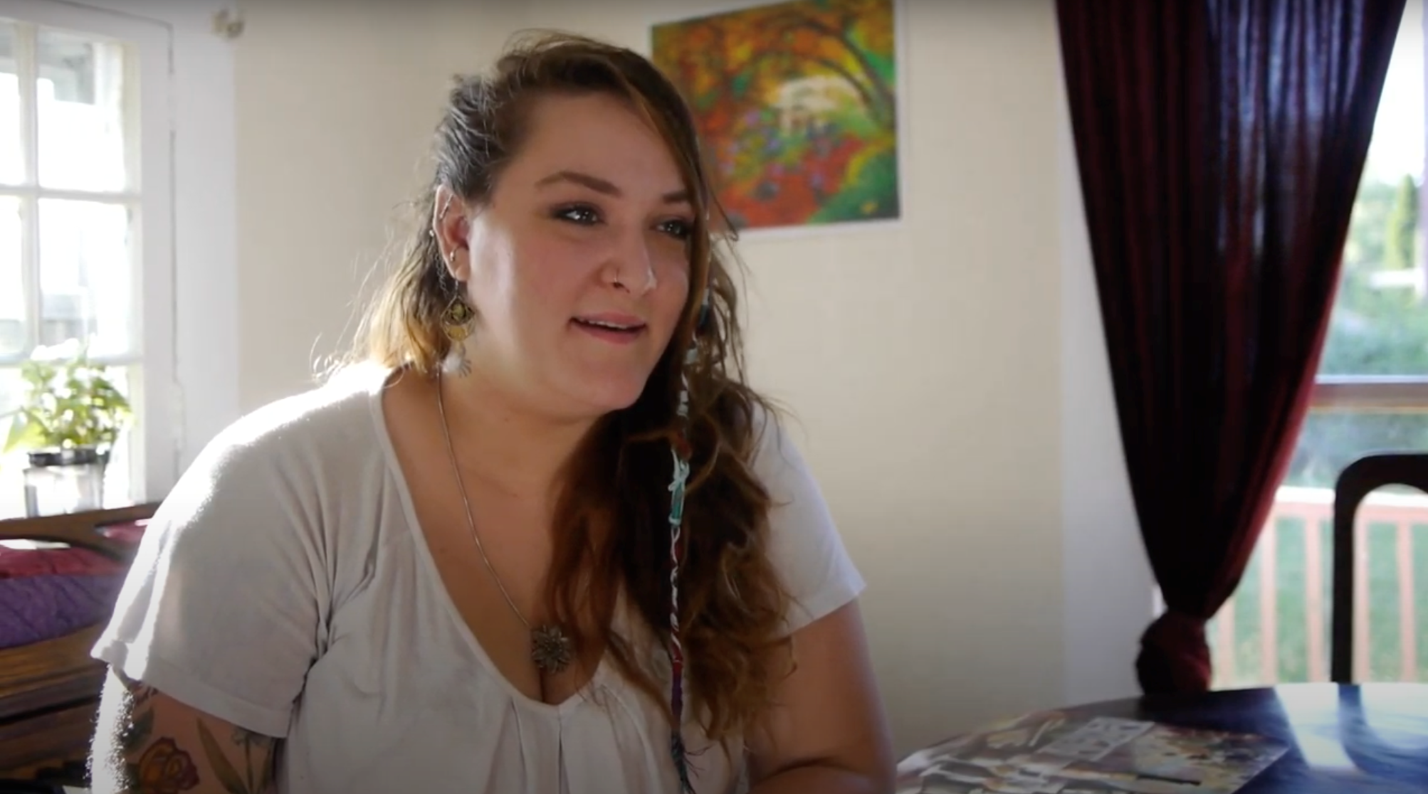 woman with long dark hair wearing a white shirt talking about her birth control to camera