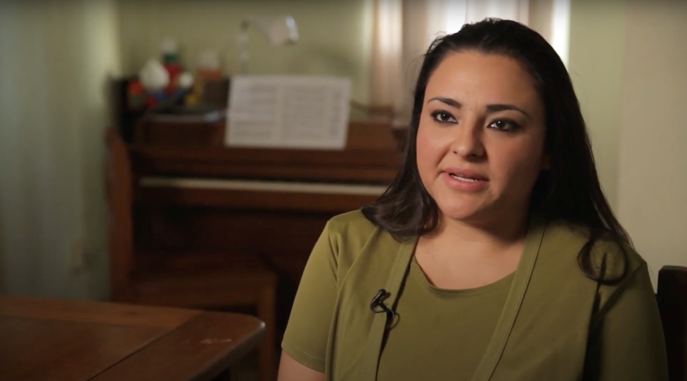 bipoc woman with dark hair and a green top talking about her birth control to camera