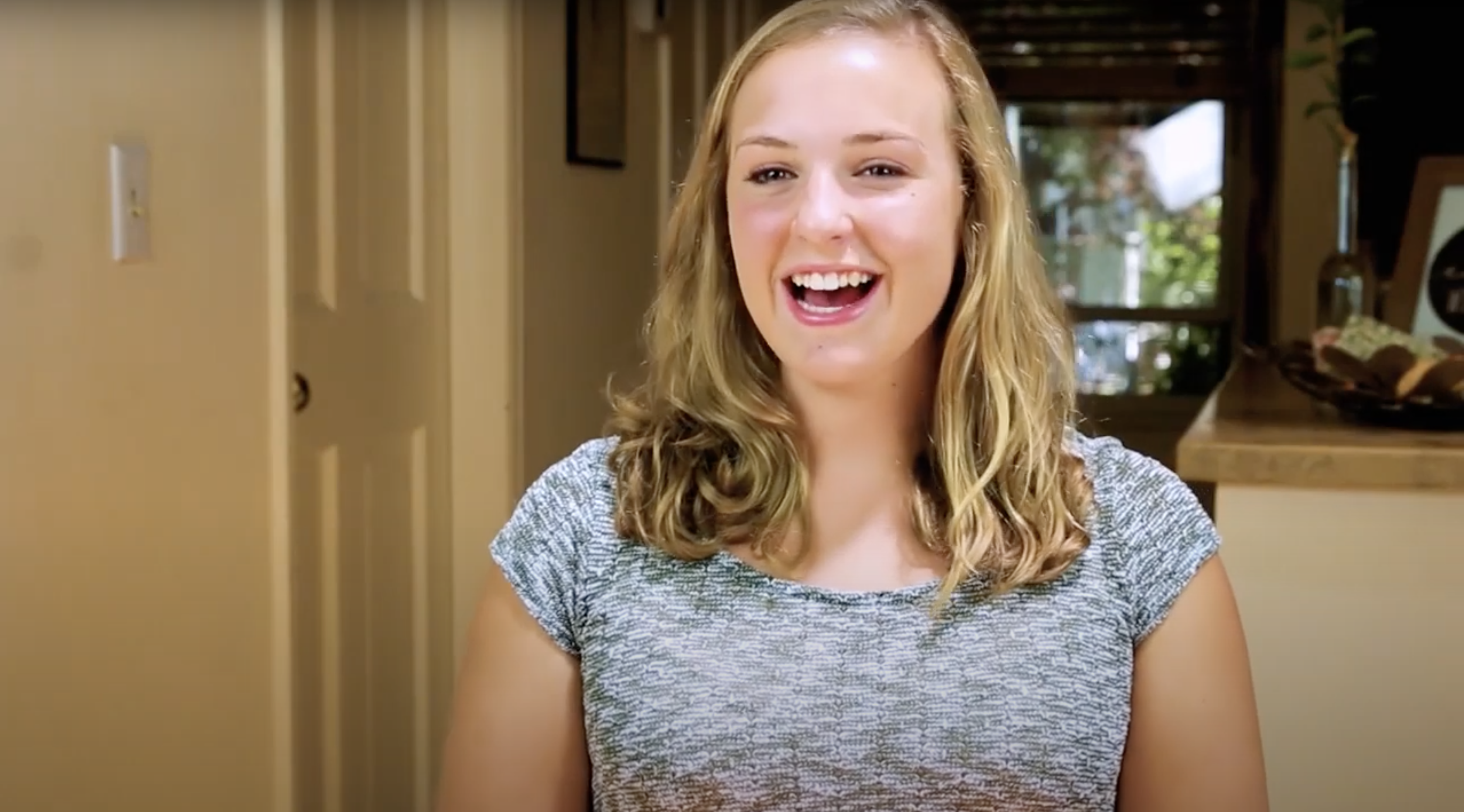 blonde girl wearing a blue shirt smiling 