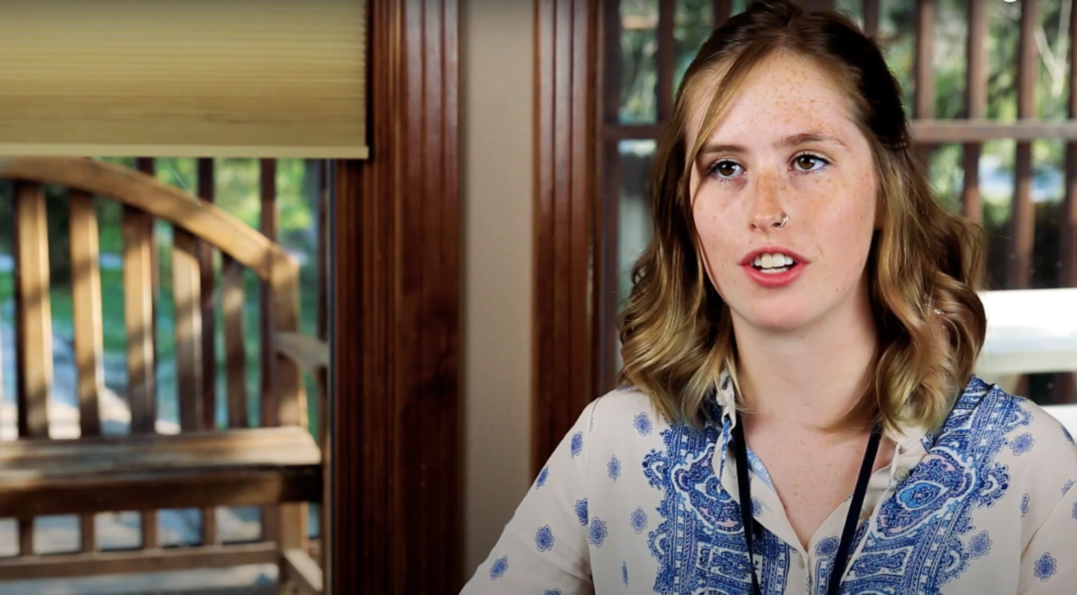 white woman with brown hair wearing a white and blue shirt talking about her birth control to camera