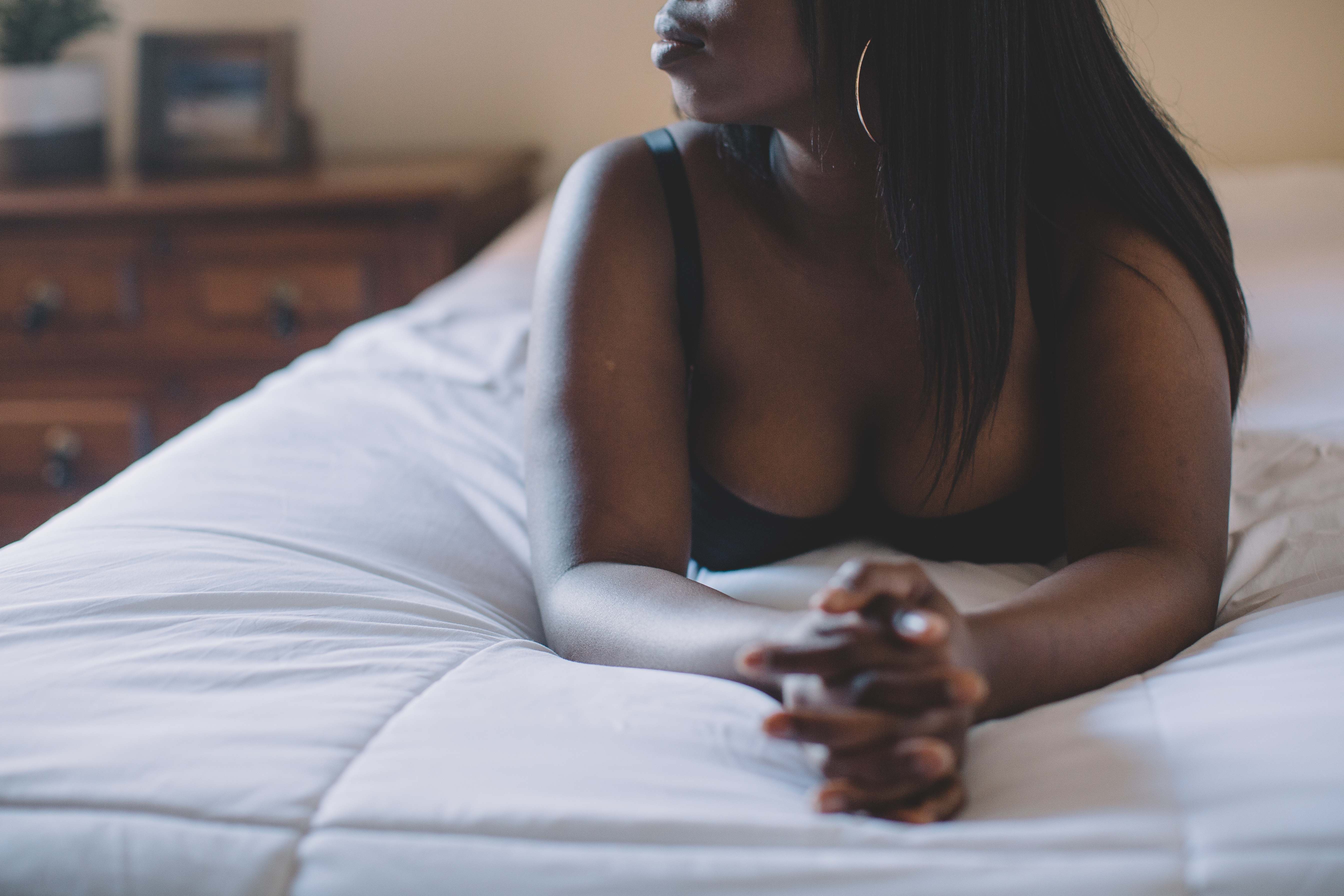 BIPOC woman wearing a bra and lying on her bed while looking to the left