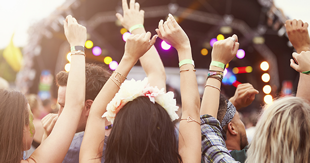 group of people with their arms raised at an outdoor concert