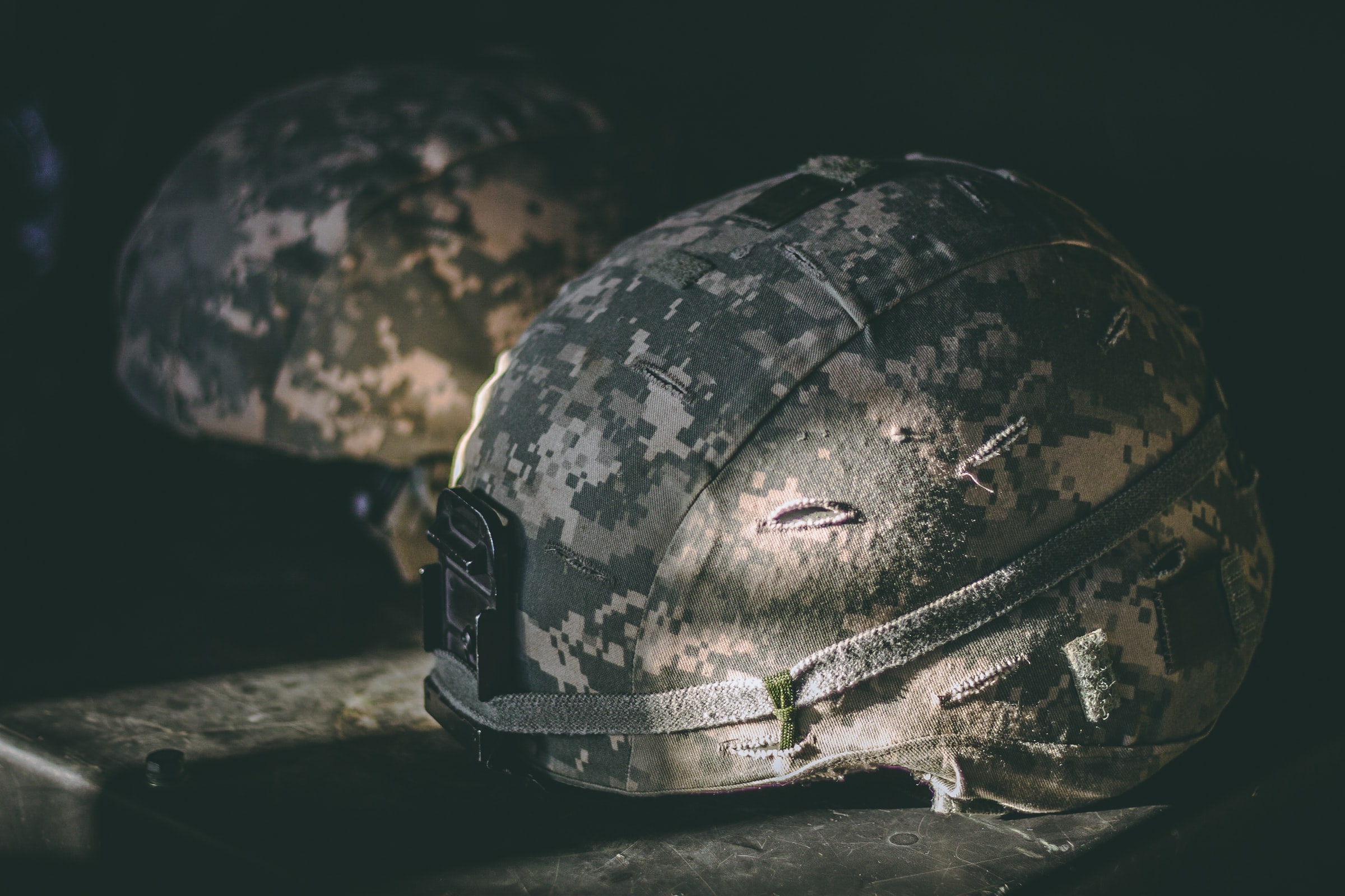 two helmets covered in a camouflage pattern resting on a table