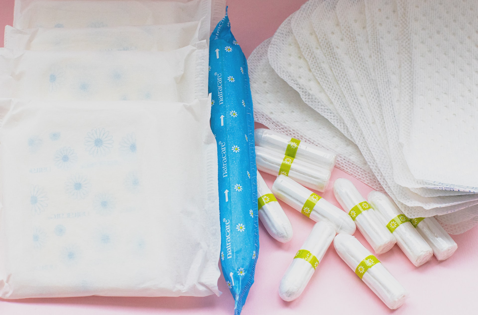 various menstrual products displayed on a pink background