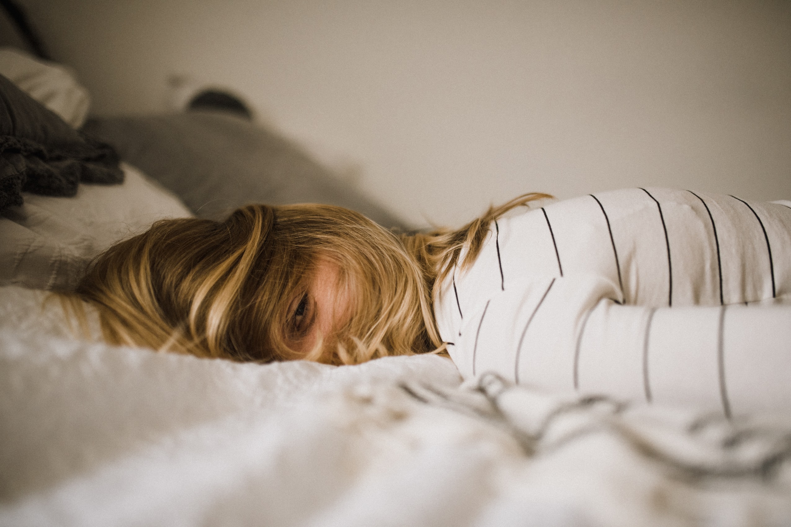 blonde woman in striped shirt lying face down with her hair covering her face