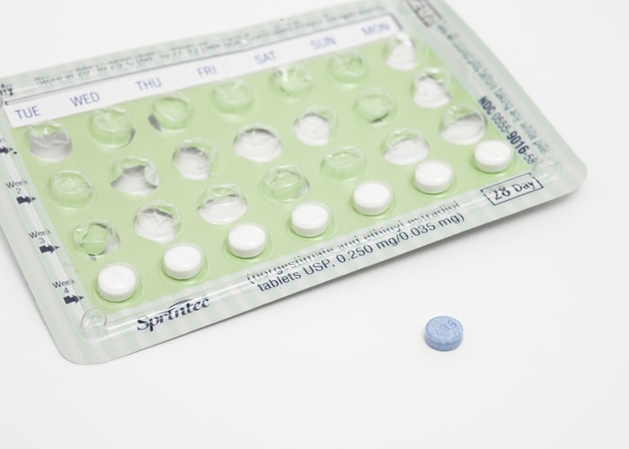 A blue tablet next to a monthly pack of oral contraceptives that is 3/4 empty