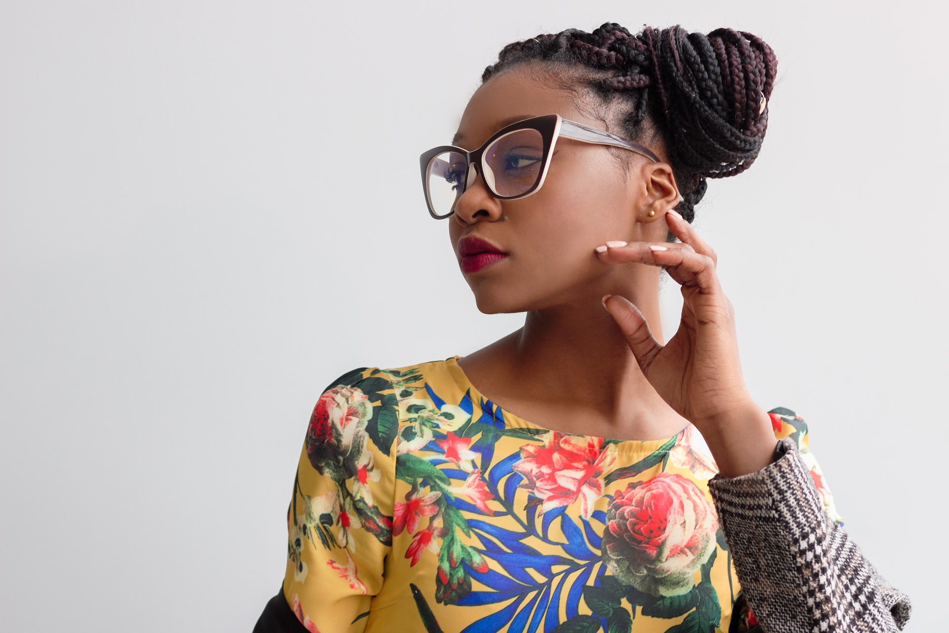 black woman in glasses wearing a floral shirt looking to the left