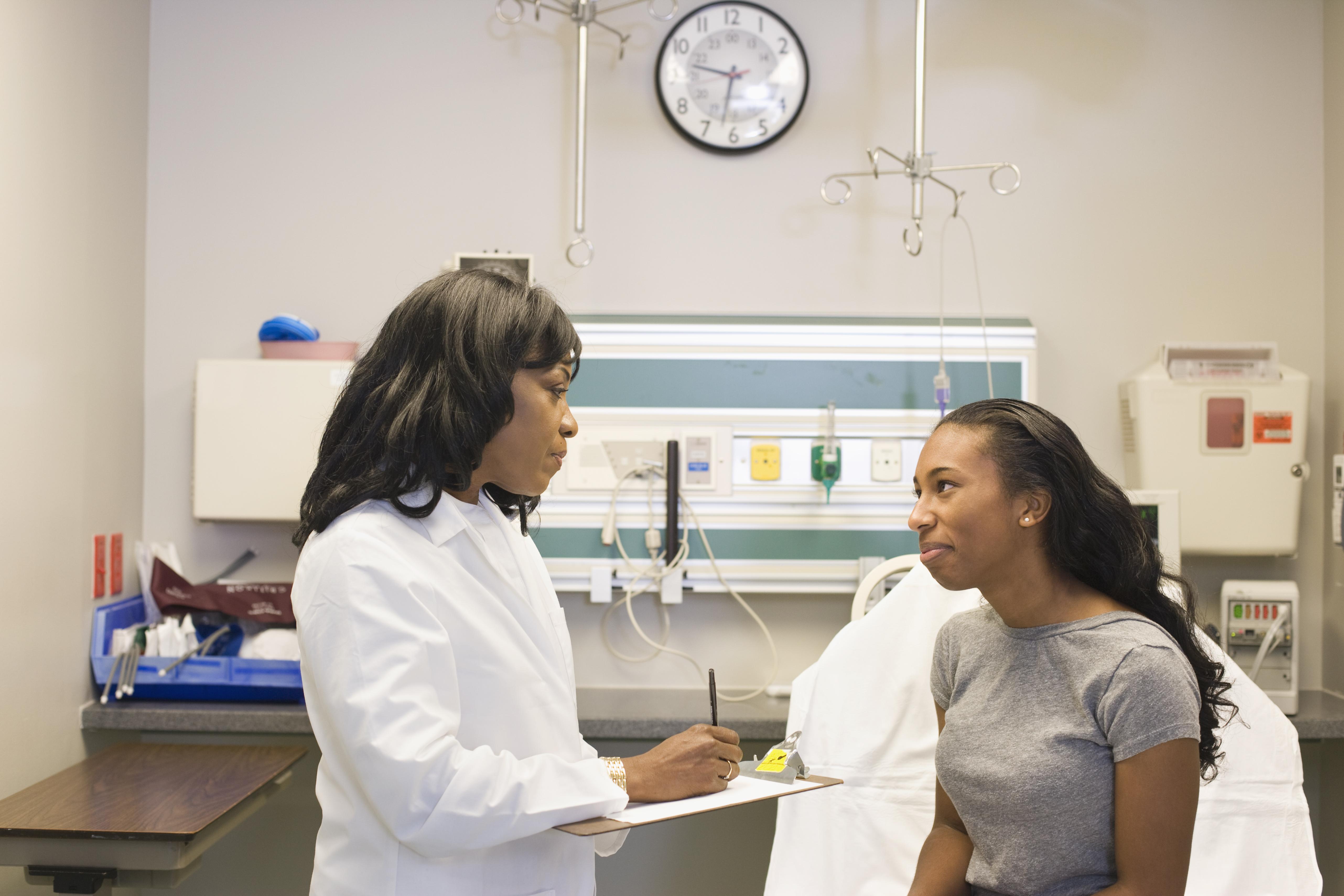 black female medical provider counseling a young black female patient in an exam room