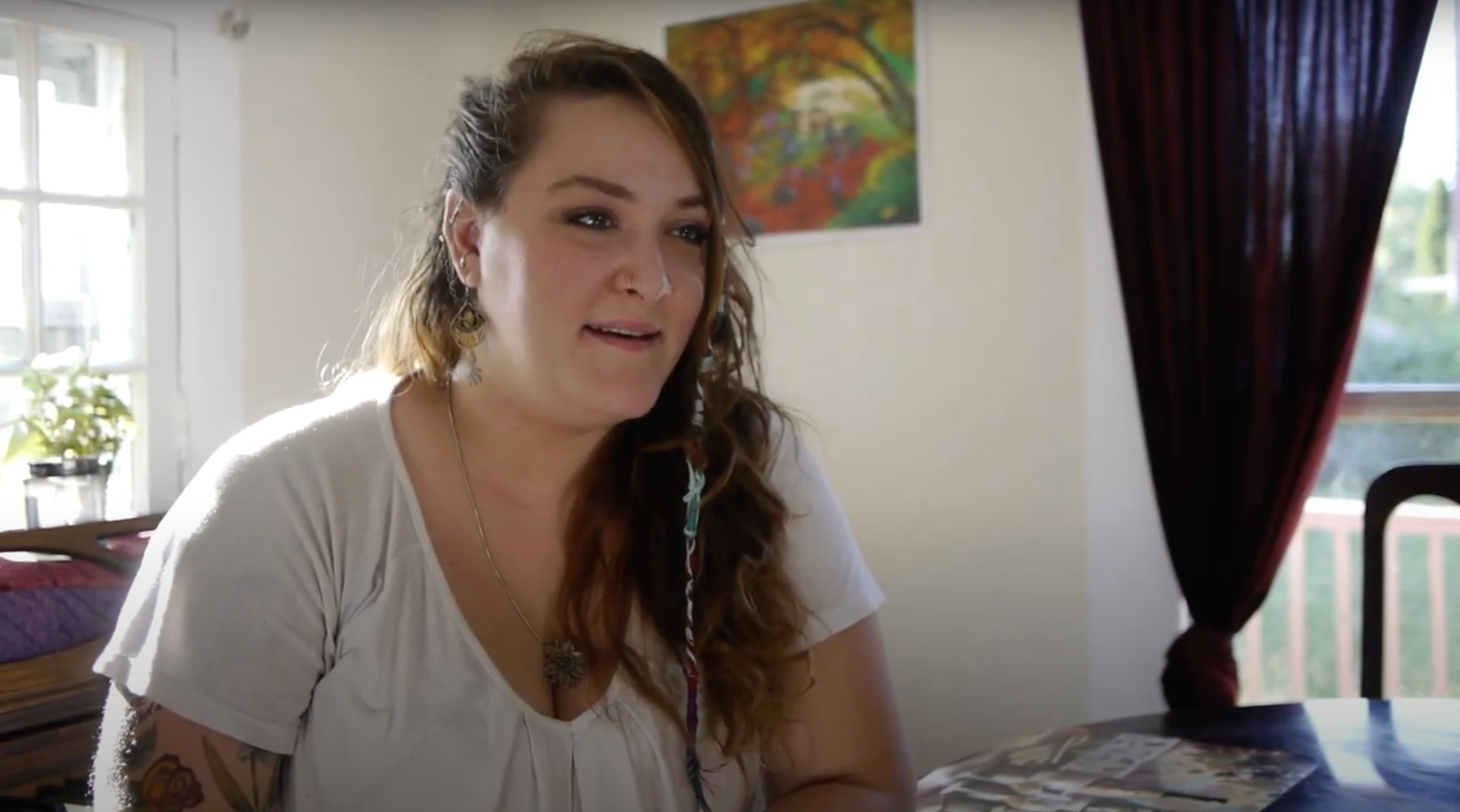woman with long dark hair wearing a white shirt talking about her birth control
