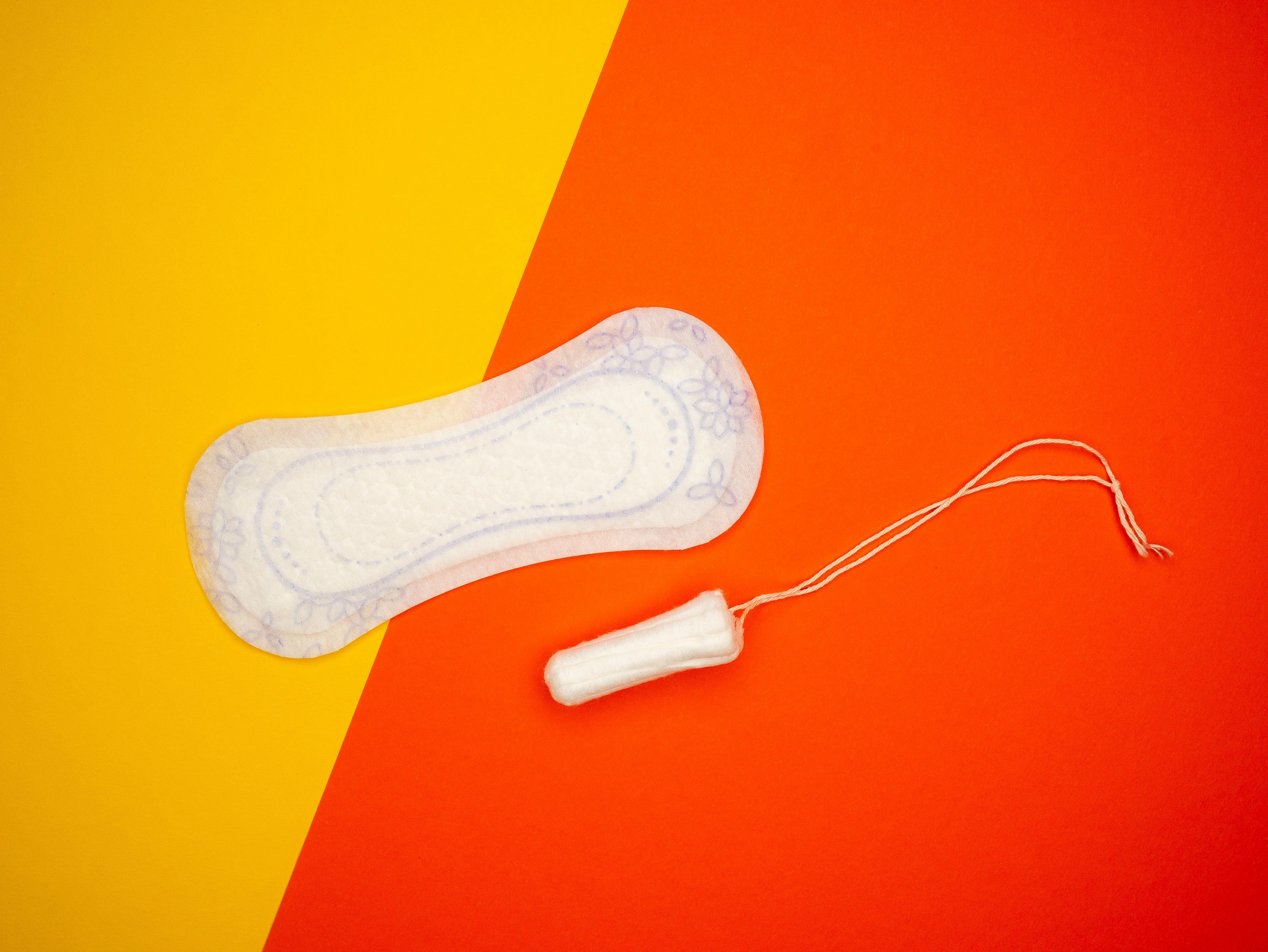 sanitary pad and tampon on a yellow and red background