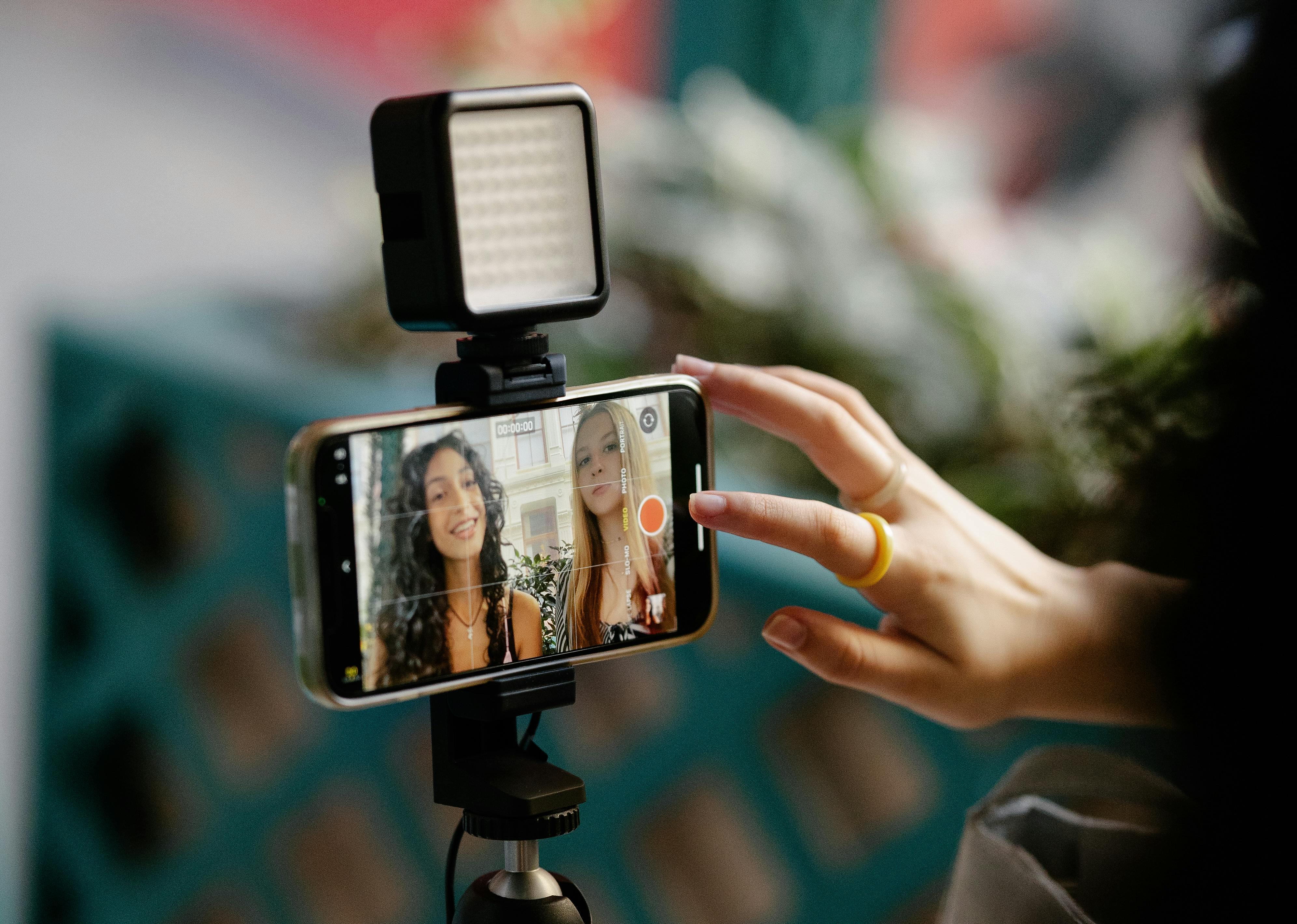 two young females getting ready to record a video of themselves using a smartphone