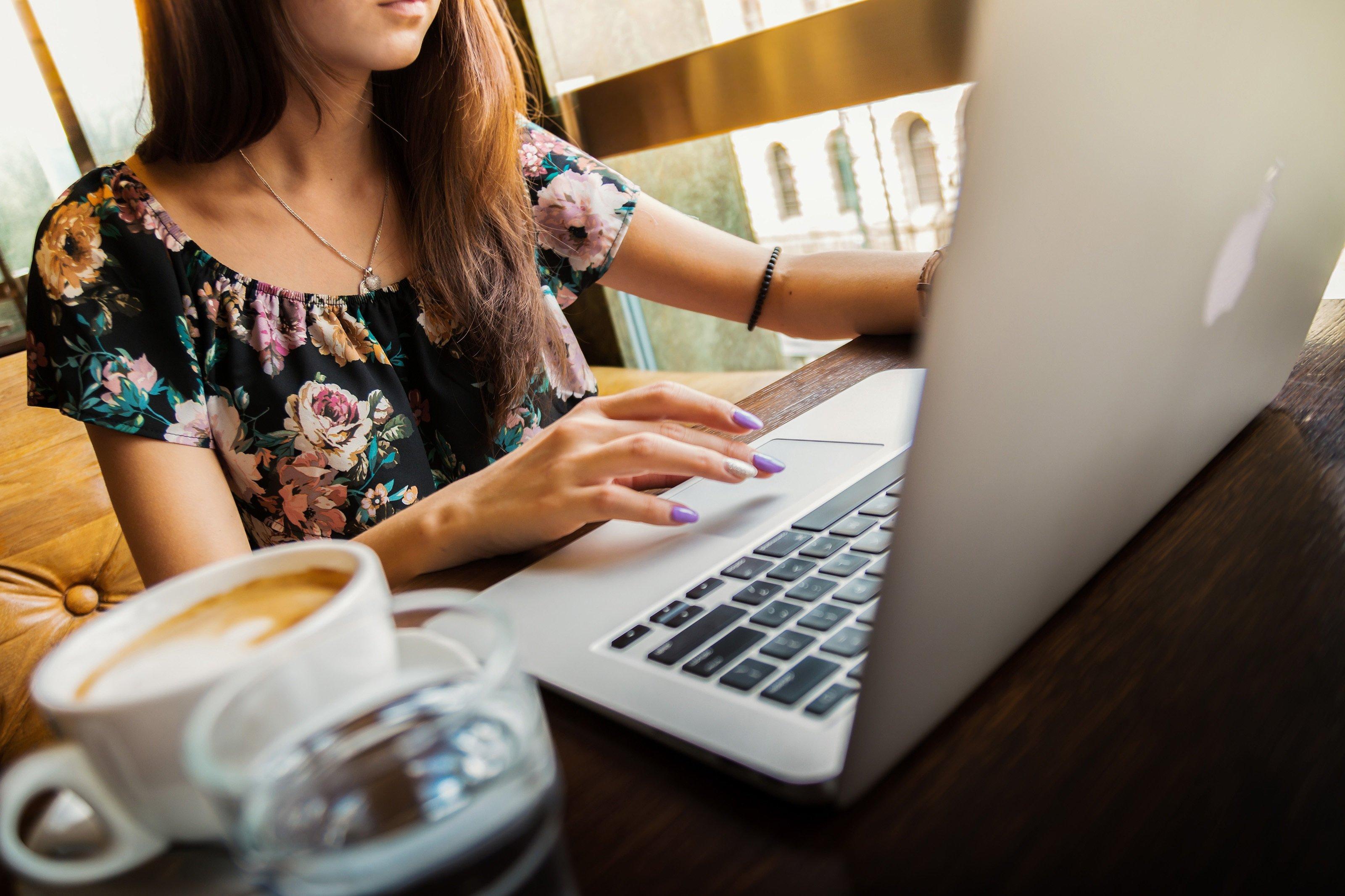woman in floral top and long hair using a laptop computer