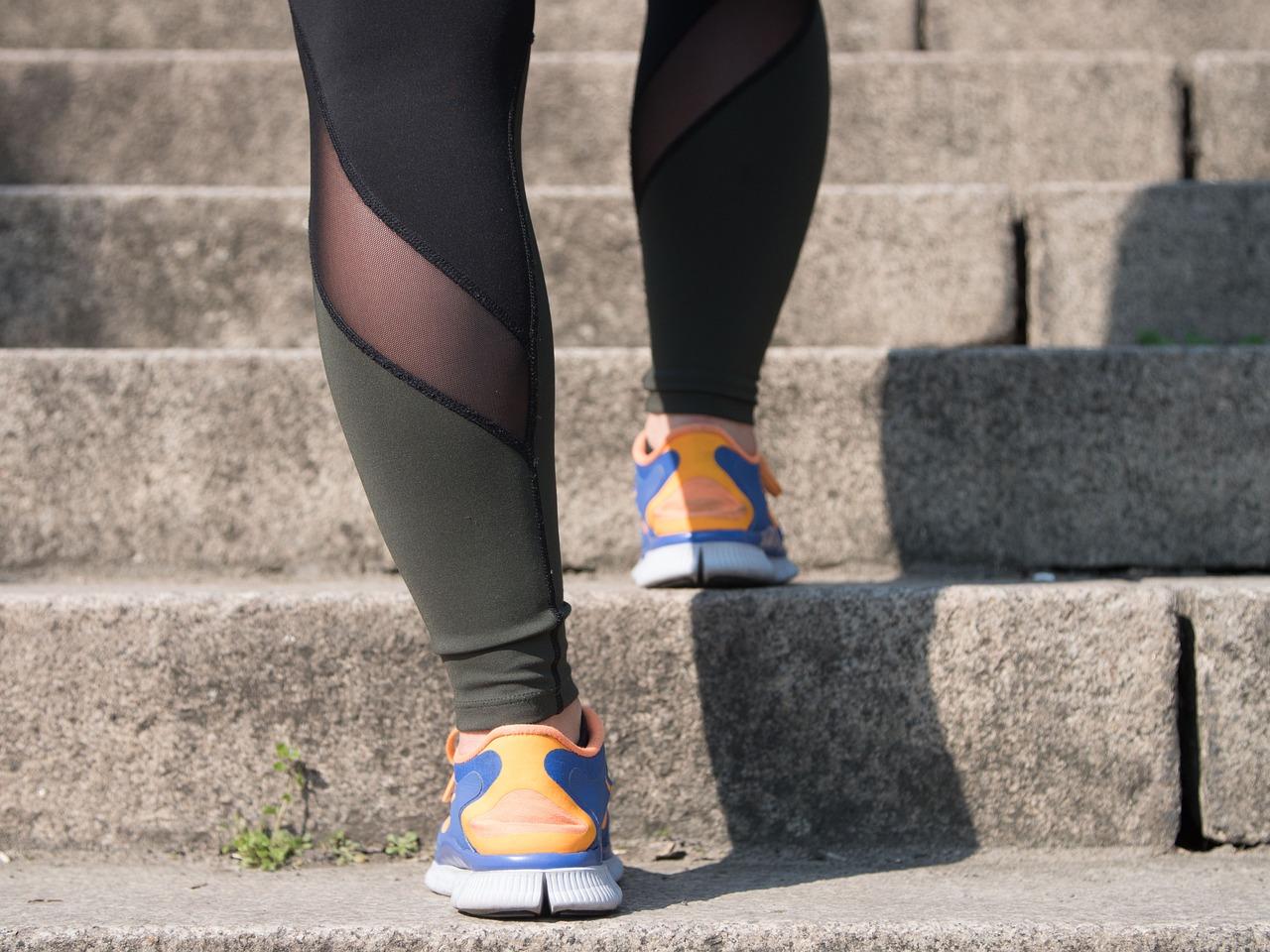 person wearing blue and orange sneakers getting ready to climb concrete stairs for exercise