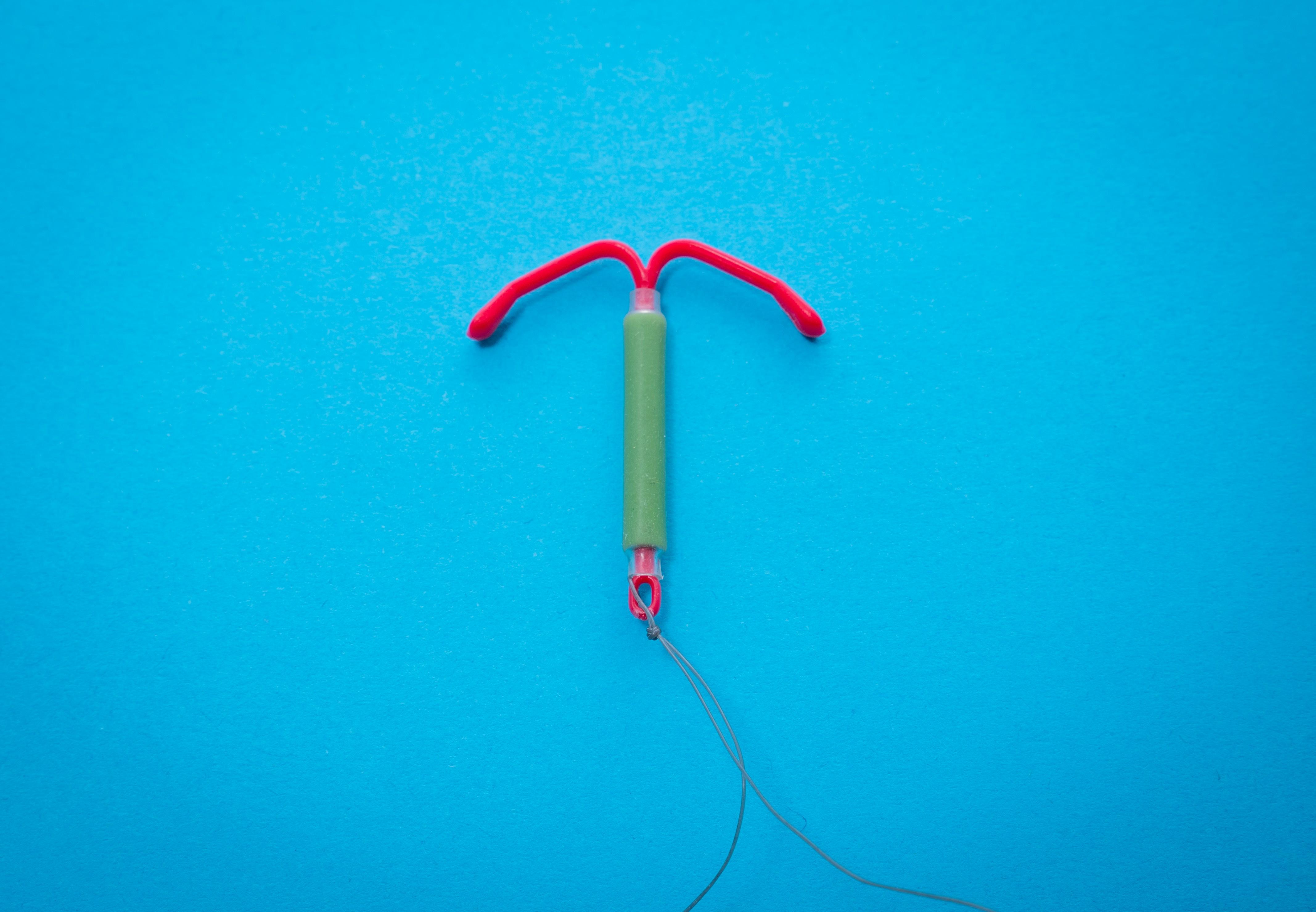 red and green IUD with string on a blue background