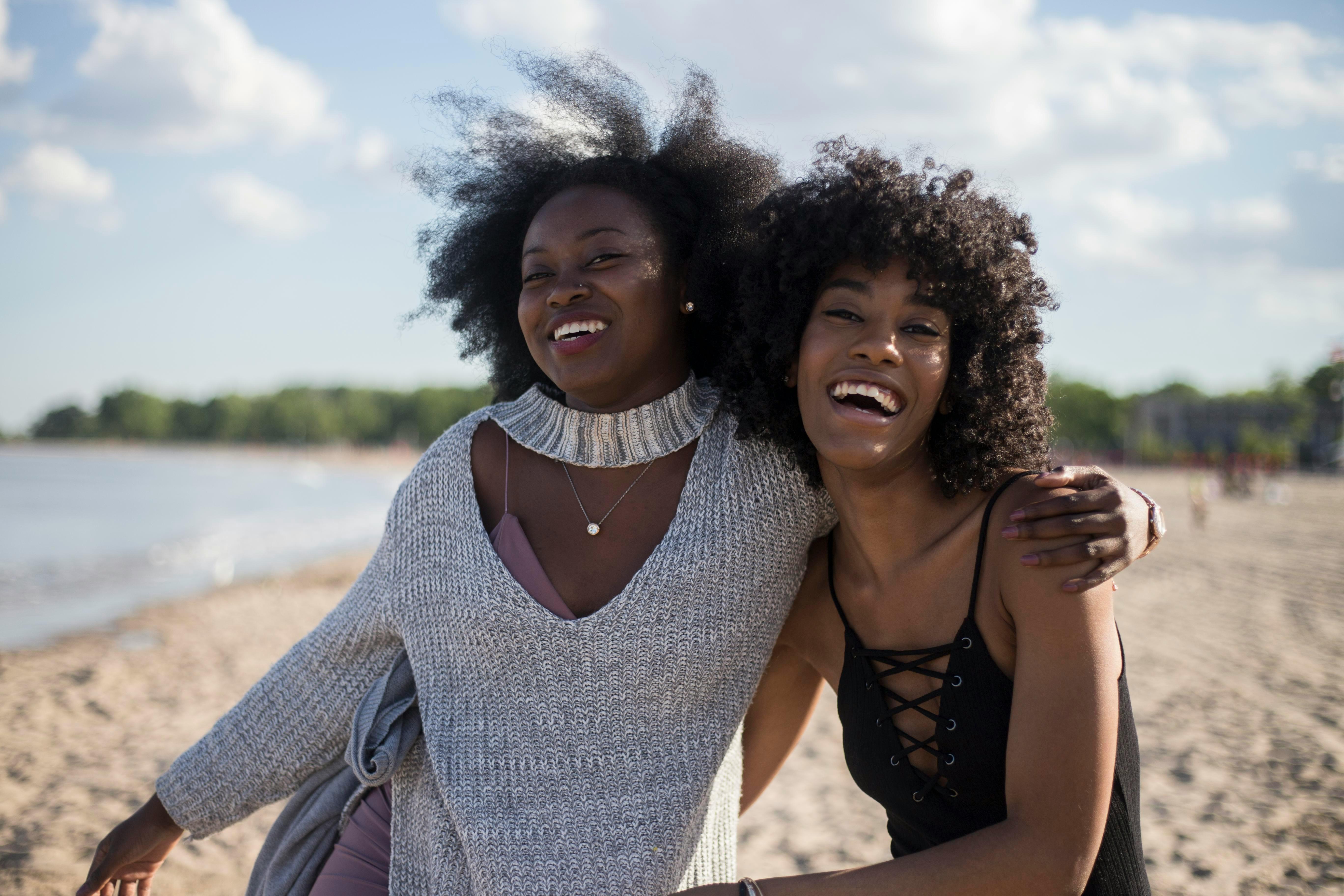 two female POC smiling and laughing together on the beach