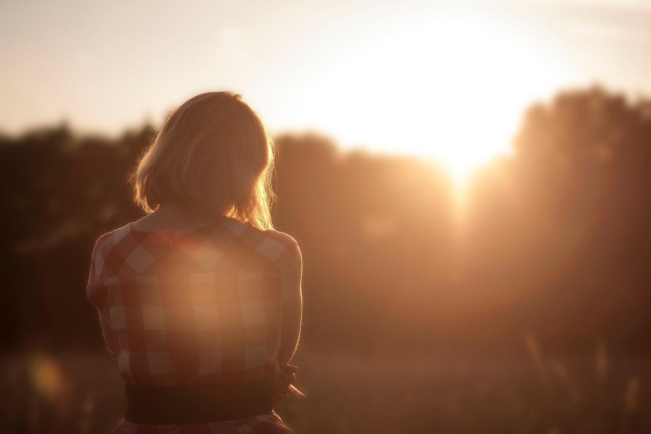 young woman in plaid shirt, alone, looking at the sunset
