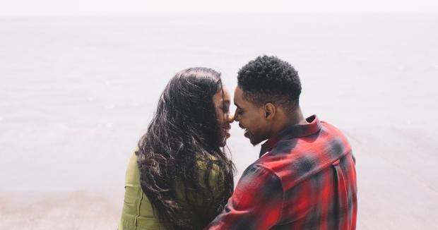 BIPOC woman and BIPOC man smiling and leaning in to kiss