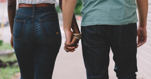 couple shown from the waist down holding hands and walking