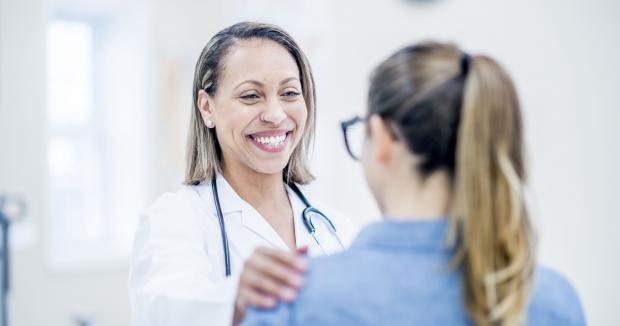 female medical provider smiling with her hand on a patient's shoulder