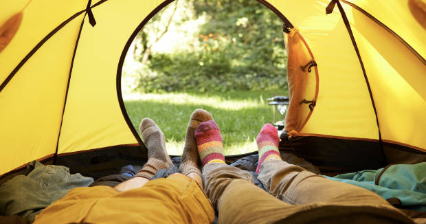 two pairs of legs lying down in a yellow tent facing the tent entrance