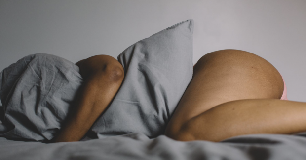 black woman lying in bed and hugging a pillow