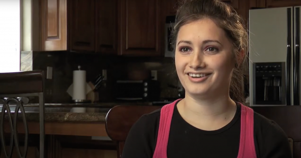 young woman in black shirt and pink tanktop talking about her birth control in her kitchen