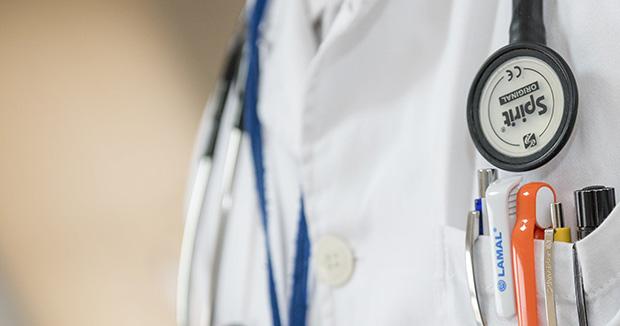 closeup of a doctor's white coat with a stethoscope and pens in a pocket