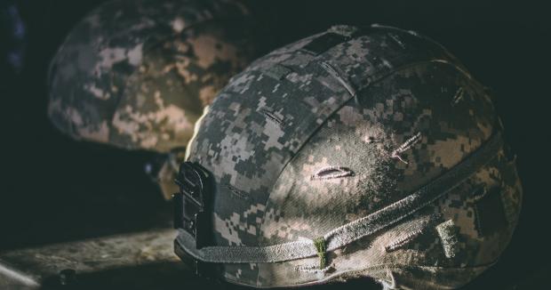 two helmets covered in a camouflage pattern resting on a table