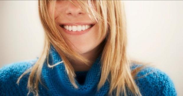 closeup of woman from the nose down with blonde hair smiling in blue sweater