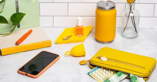 assortment of items on a countertop, including phone, pen, nail polish, tampons, wallet, birth control pills