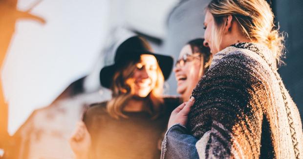 three woman laughing while standing outside