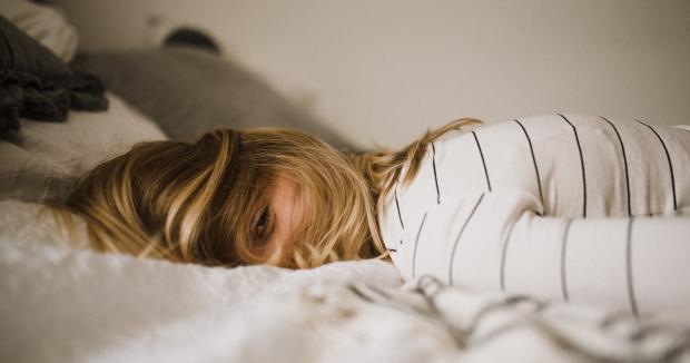 blonde woman in striped shirt lying face down with her hair covering her face