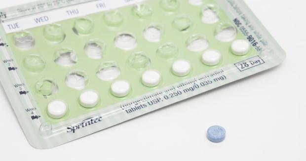 A blue tablet next to a monthly pack of oral contraceptives that is 3/4 empty