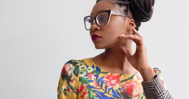 black woman in glasses wearing a floral shirt looking to the left