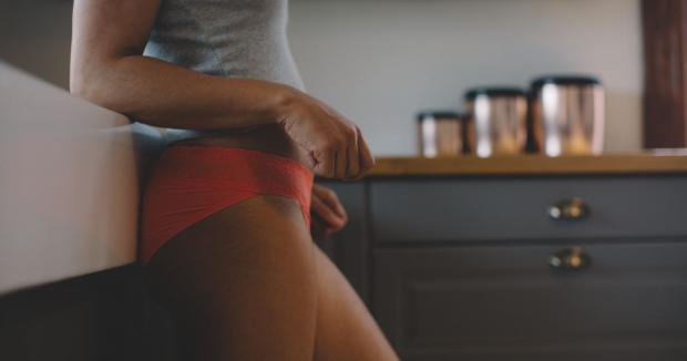 woman in a tank top and underwear standing in the kitchen