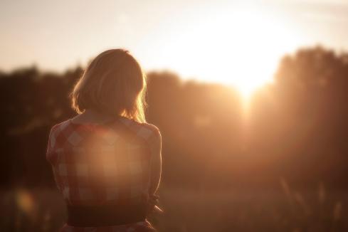 young woman in plaid shirt, alone, looking at the sunset