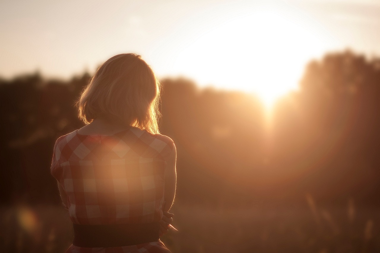young woman in plaid shirt, alone, looking at the sunset